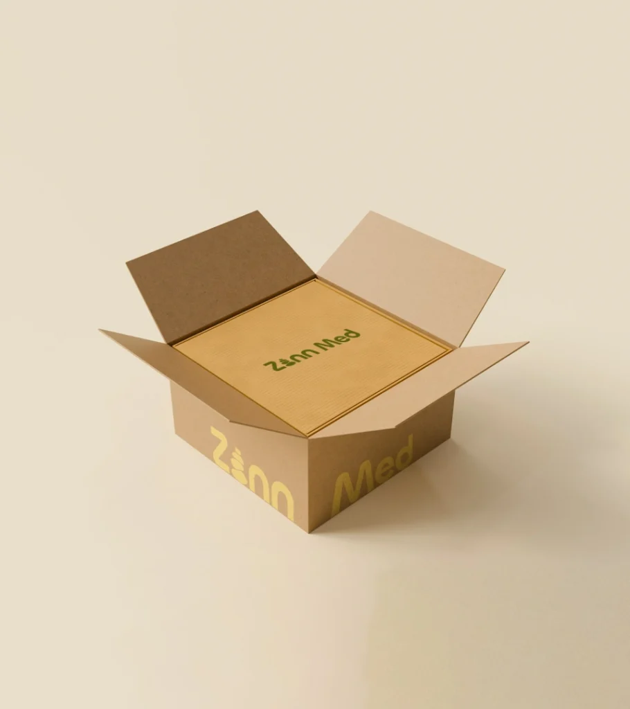 An open cardboard box with "Zann Med" printed on the side and top, containing a flat rectangular item with the same text.